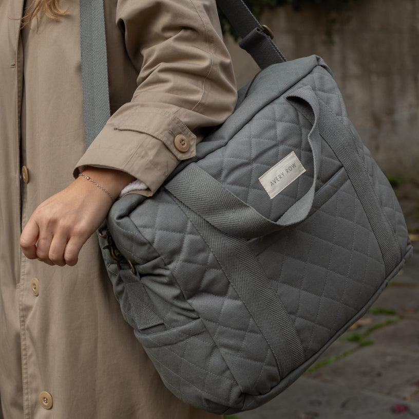 Person holding a quilted gray bag with a visible brand label.