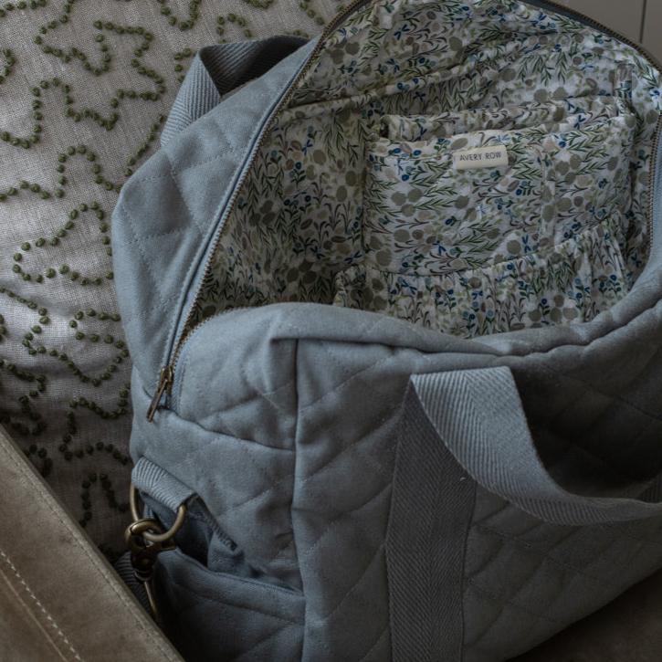 Gray quilted bag with floral lining on a textured surface