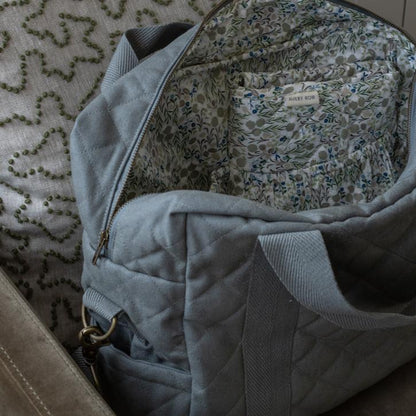 Gray quilted bag with floral lining on a textured surface