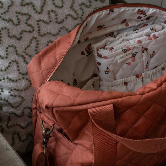 Pink quilted bag with floral-patterned fabric inside, on a textured surface.