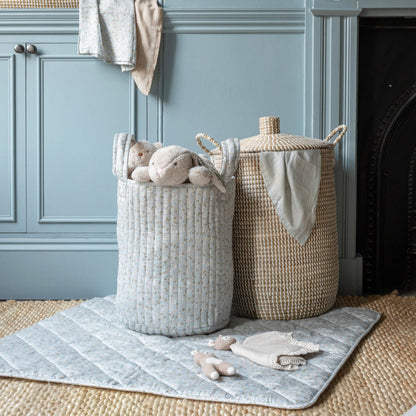 Two woven baskets with toys on a rug in a room with blue walls and a fireplace.