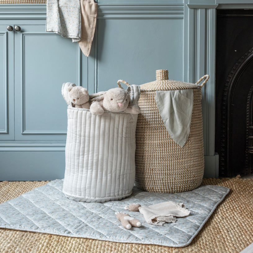 Two laundry baskets with toys on a rug in a room with blue walls and a fireplace.