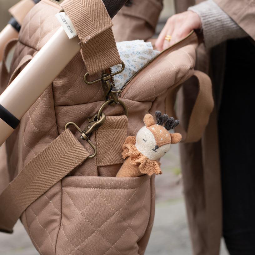 Close-up of a brown quilted bag with a plush deer toy attached to a strap.