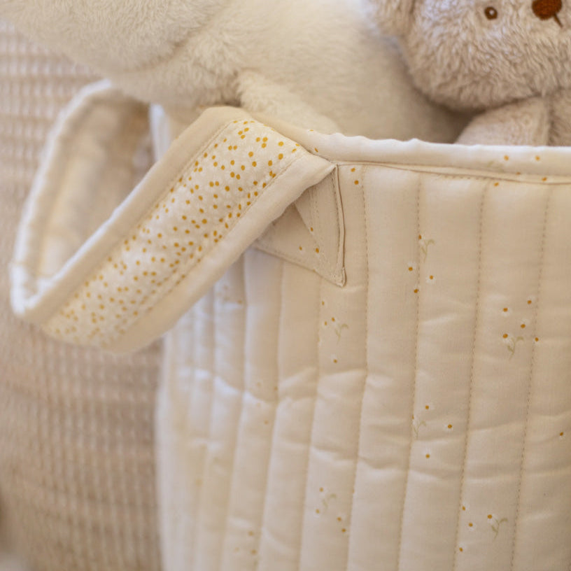 Close-up of a baby's quilted jacket with a teddy bear on a neutral background