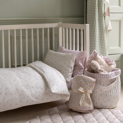 Children's bedroom with a white crib and decorative pillows and toys.