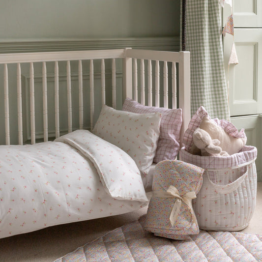 Children's bedroom with a white crib and decorative pillows and toys.