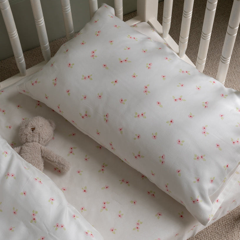 Crib with floral-patterned sheet and teddy bear