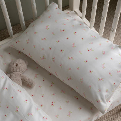 Crib with floral-patterned sheet and teddy bear