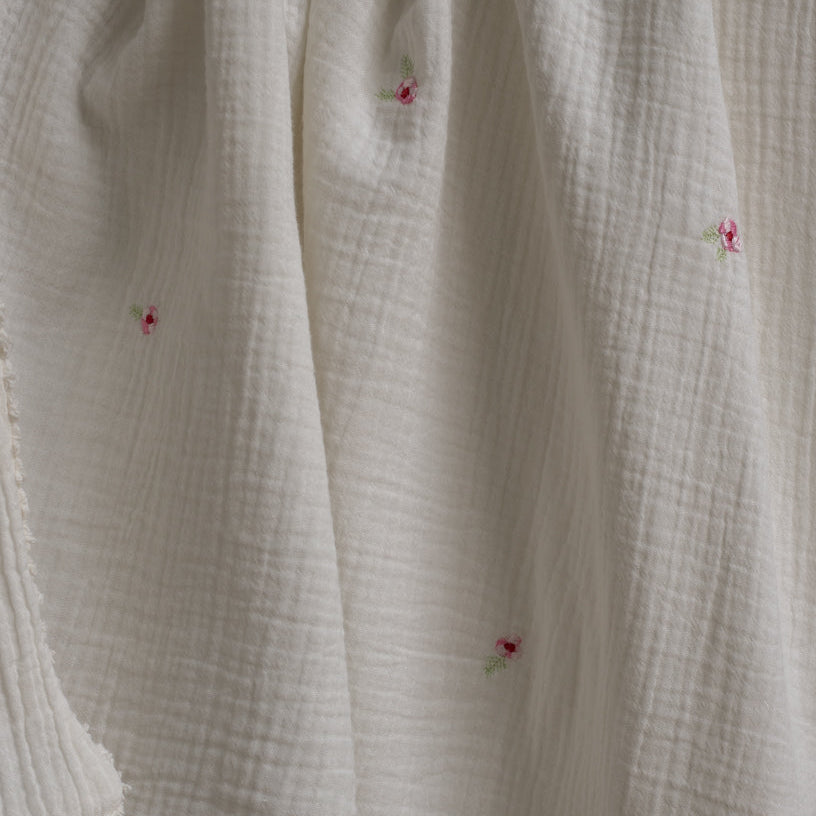 Close-up of textured fabric with small floral embroidery.