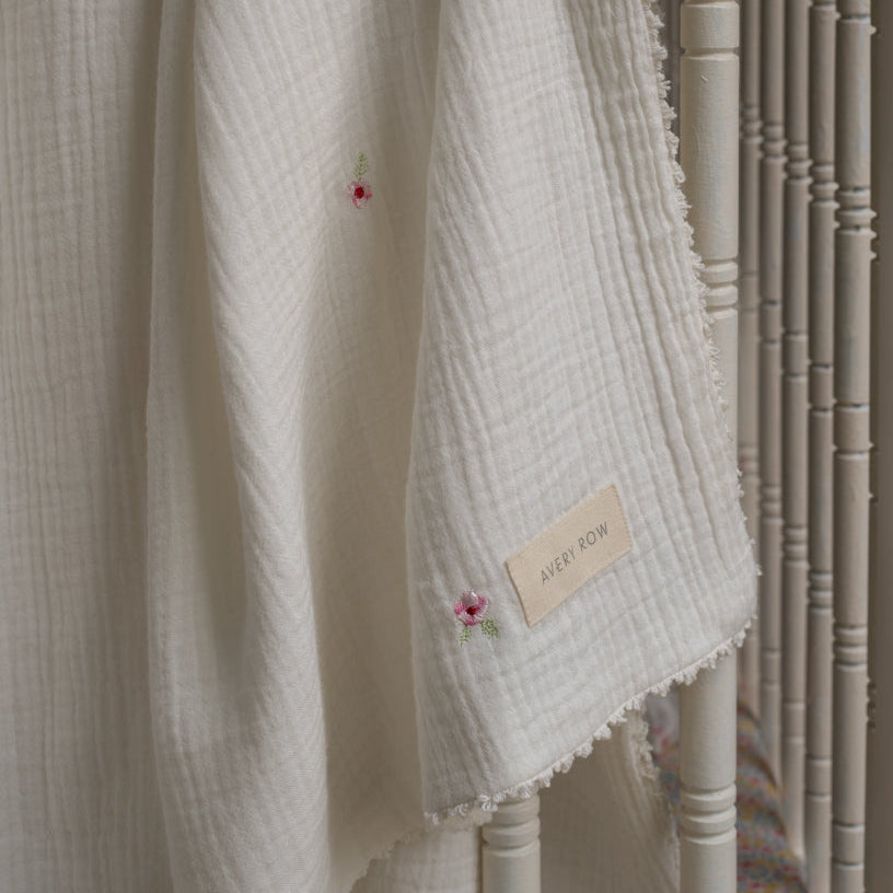 Textured white fabric with floral embroidery and a brand label on a wooden surface.