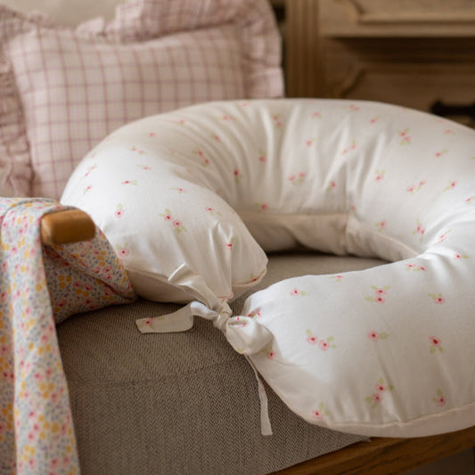 Floral-patterned U-shaped pillow on a sofa with a soft focus background