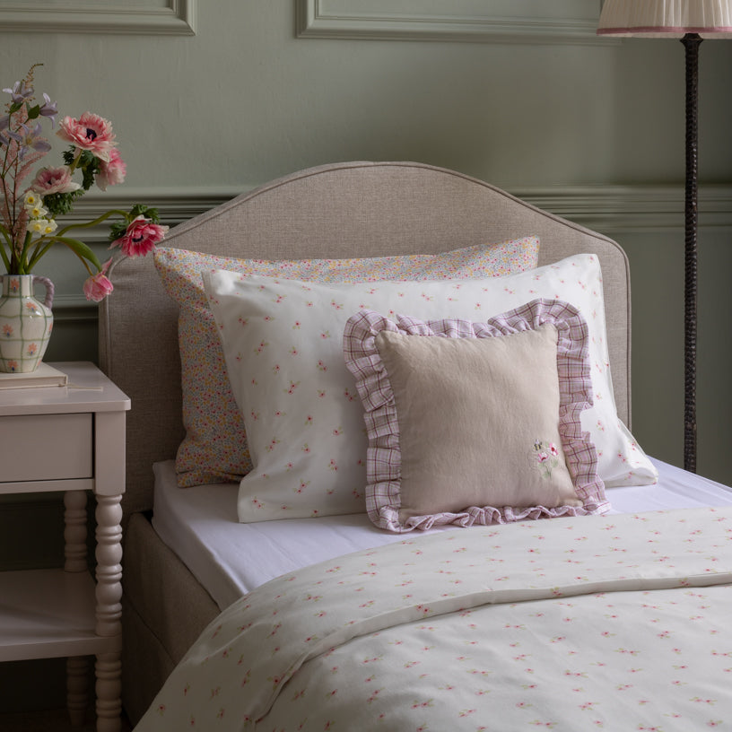 Bed with floral bedding and pillows in a bedroom setting