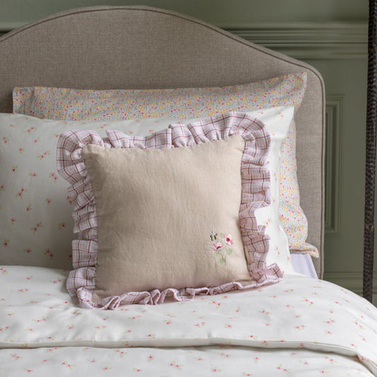 Decorative pillows with ruffled edges on a bed with floral bedding.