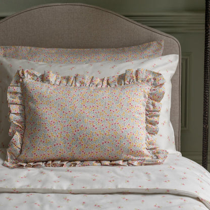 Floral patterned pillow with ruffles on a bed with matching bedding.