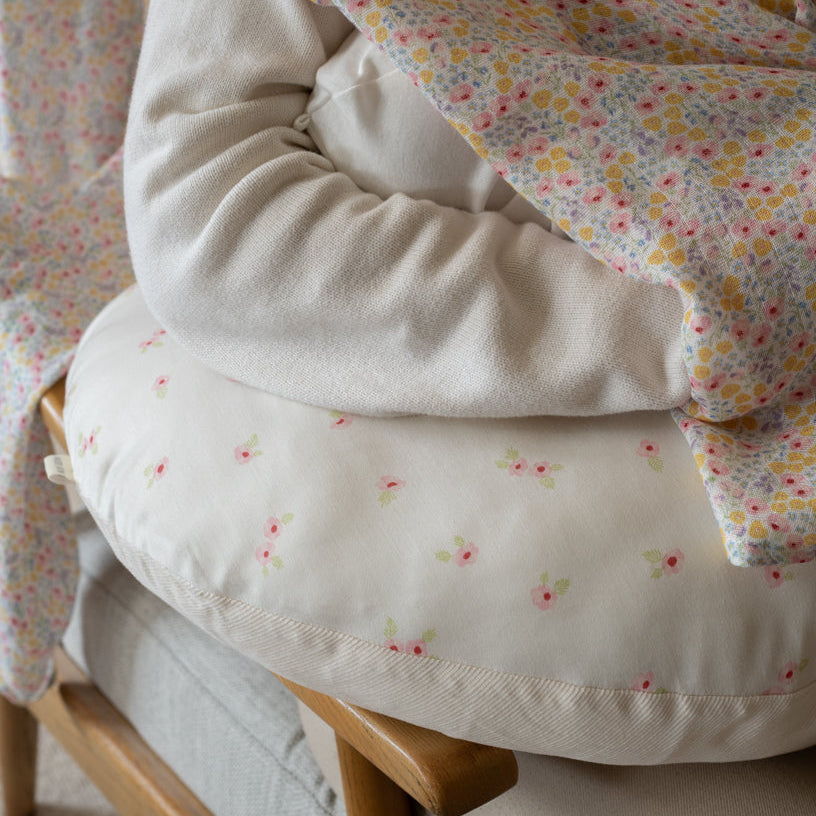 Close-up of a baby's outfit with floral patterned blanket on a chair