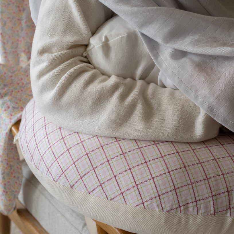 Close-up of a beige quilt with a plaid pattern draped over a chair.