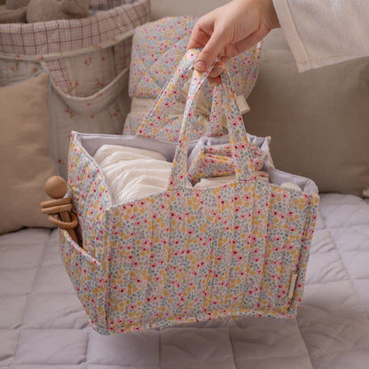 Floral-patterned diaper bag with baby items on a bed