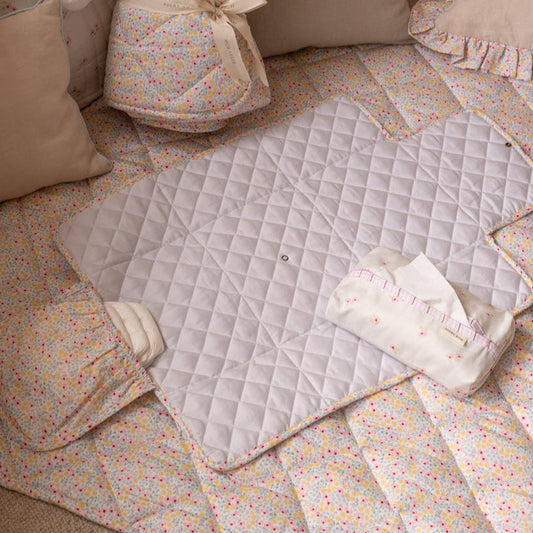 Quilted baby mat with colorful floral border on a soft surface