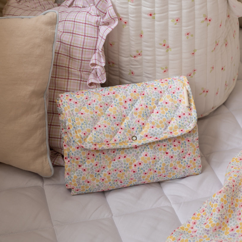 Floral-patterned clutch bag on a sofa with cushions and blankets.