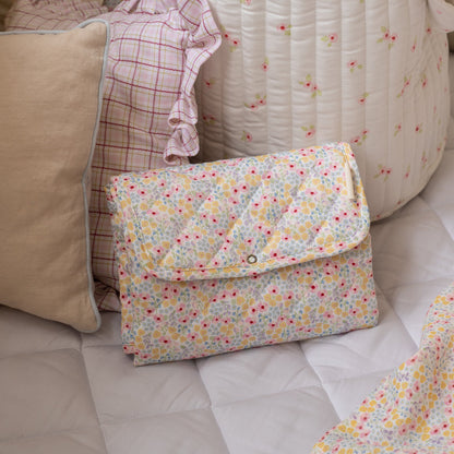 Floral-patterned clutch bag on a sofa with cushions and blankets.