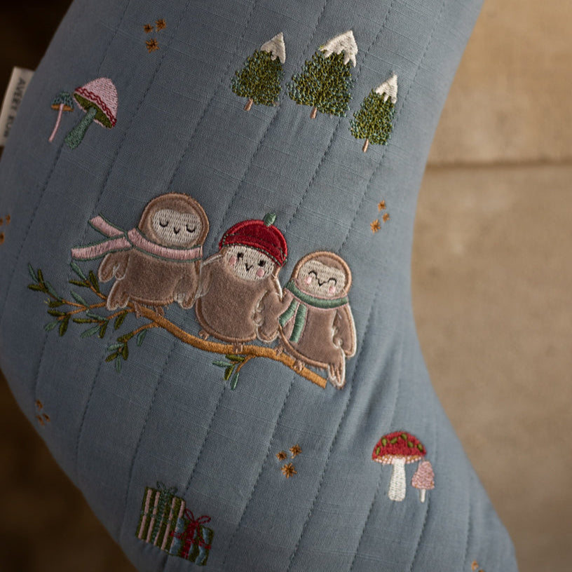 Embroidered design on a sock with three cartoon-style owls, trees, and mushrooms.