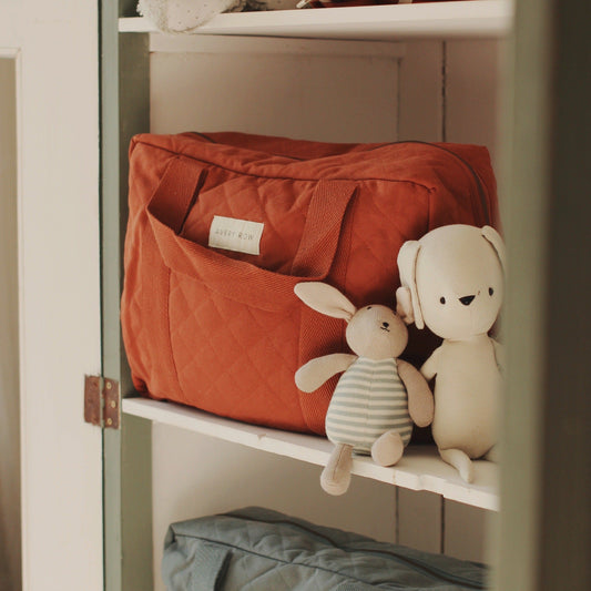 Red bag and plush toys on a shelf in a softly lit room