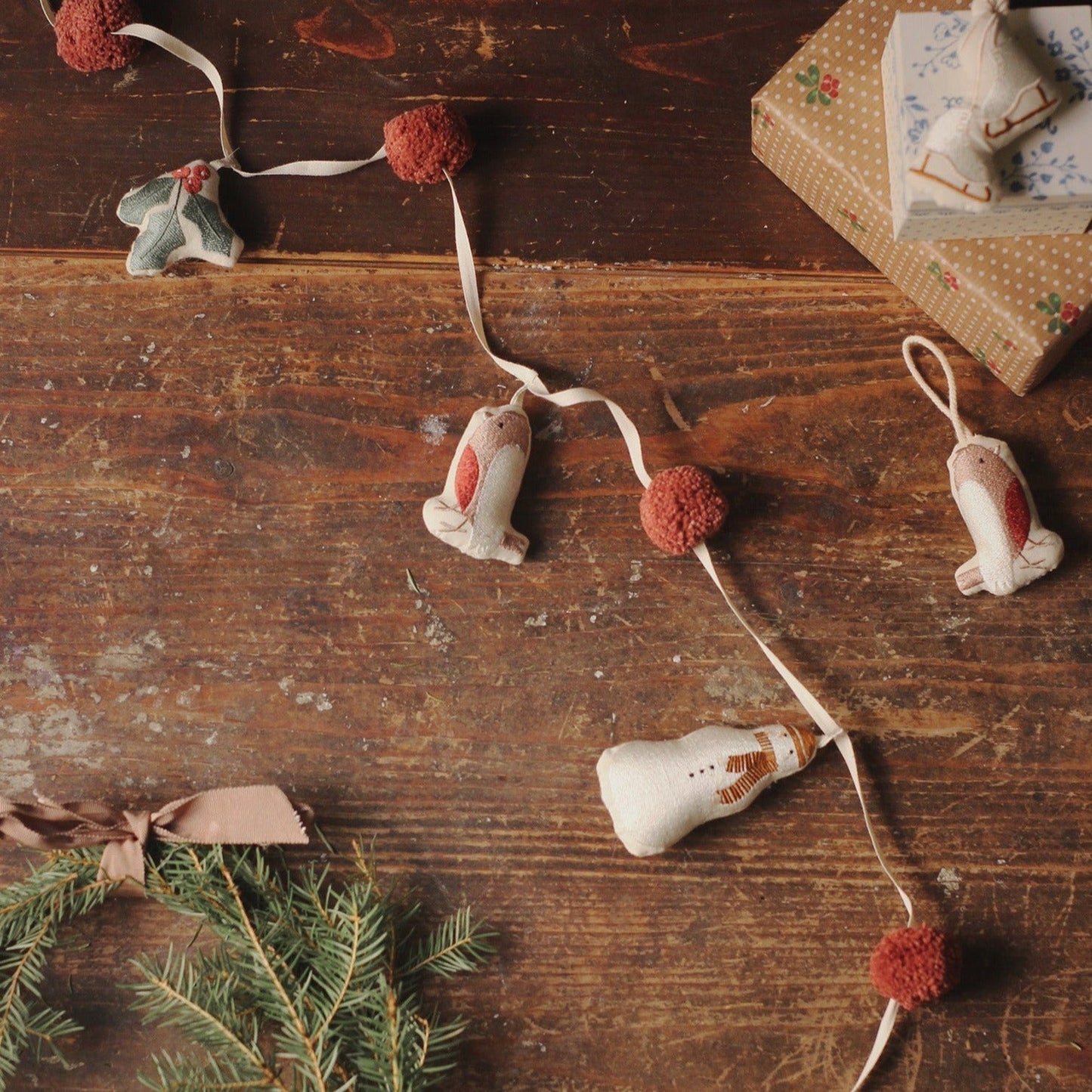 Decorative string with snowman and pom-pom ornaments on a wooden surface.