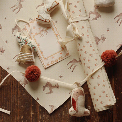 Decorative items including a rolled-up paper with a pattern, a small plush toy, and a card on a wooden surface.