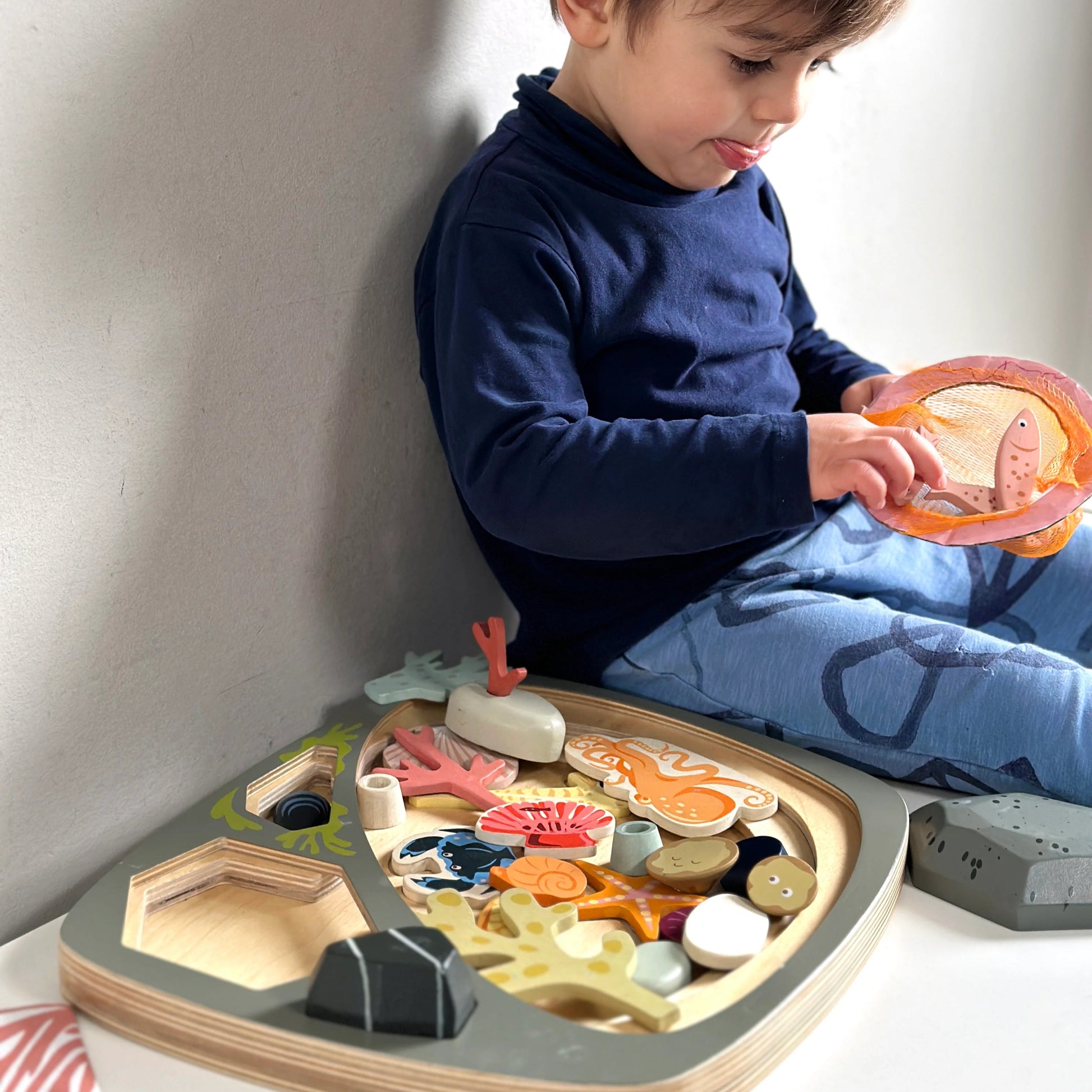 A child playing with a rock pool wooden toy set