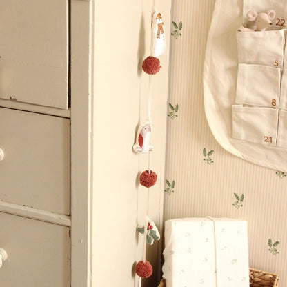 Decorative wall hanging with pom-poms and a calendar on a neutral wall.