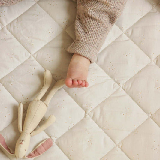 Baby's foot and toy on a quilted mattress