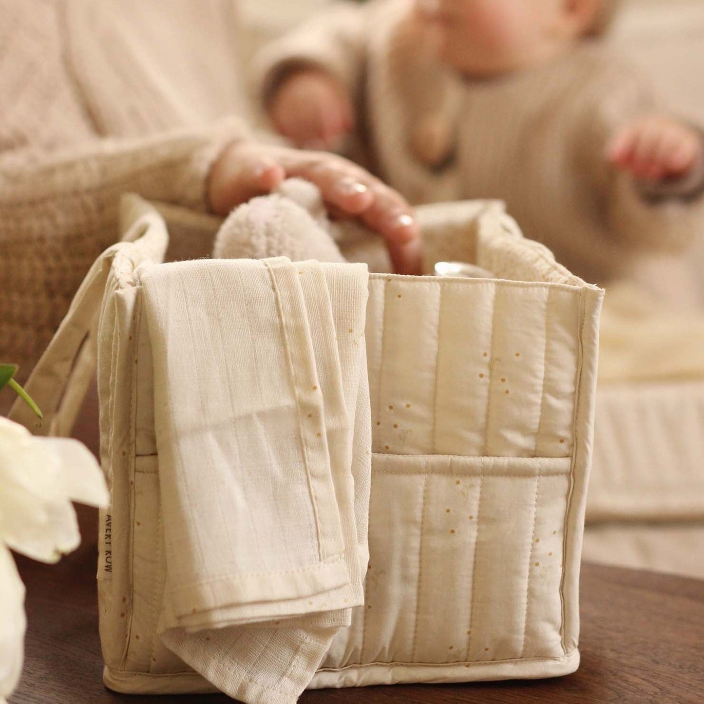 Textile product with a towel draped over it, blurred background of a person holding a baby
