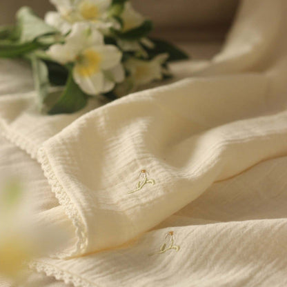 Close-up of beige fabric with floral embroidery, blurred flowers in the background