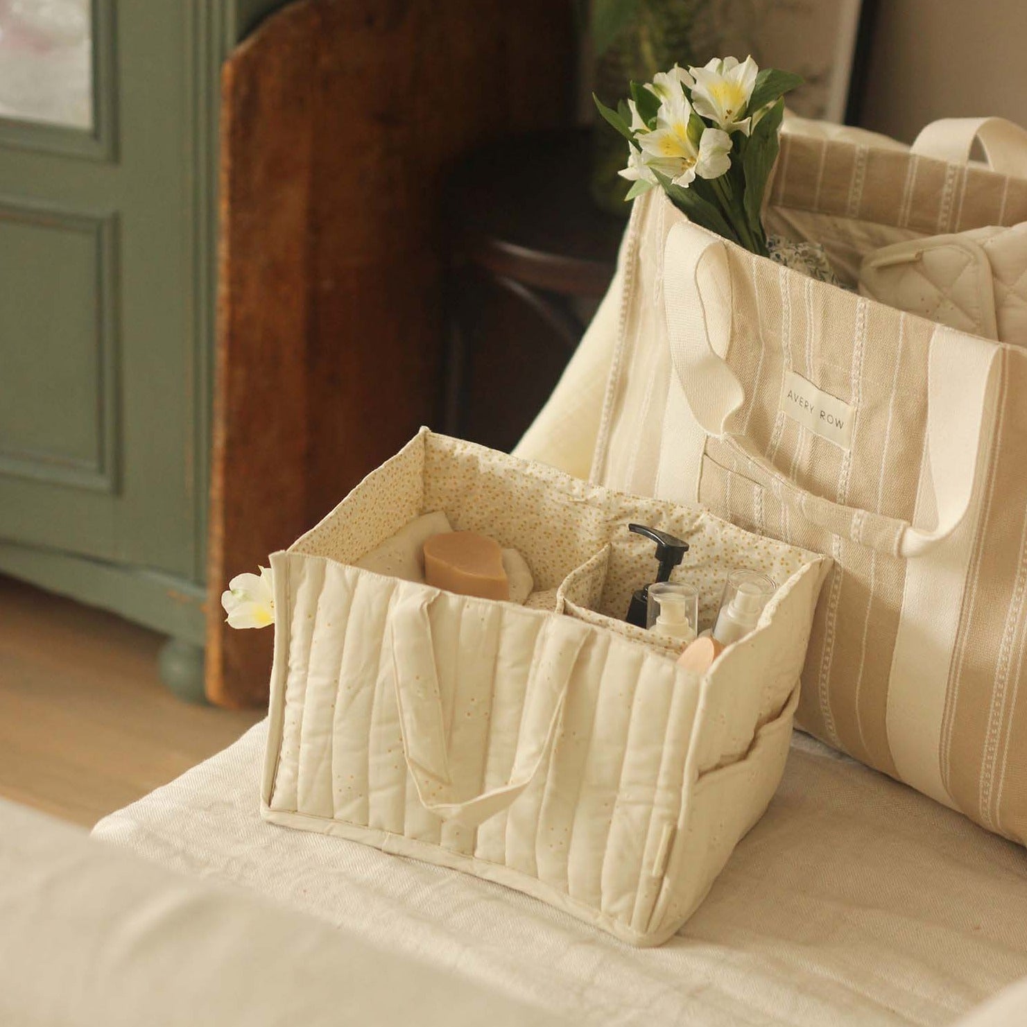 Beige quilted tote bag with floral arrangement on a bed