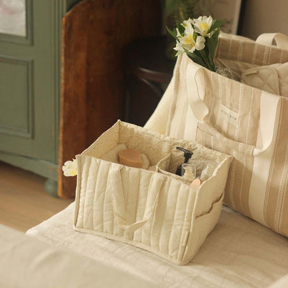 Beige quilted tote bag with floral arrangement on a bed