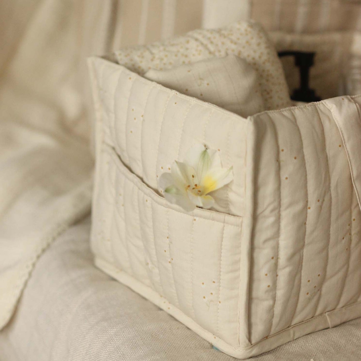 Quilted fabric basket with a flower on a beige sofa