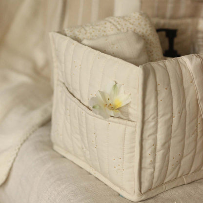 Quilted fabric basket with a flower on a beige sofa