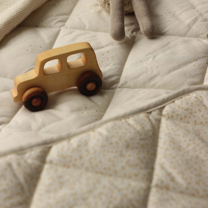 Wooden toy car on a textured beige surface