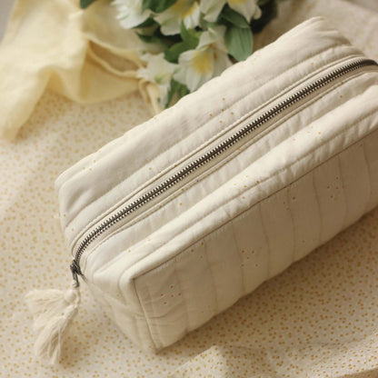 Beige quilted pouch with a zipper on a light background