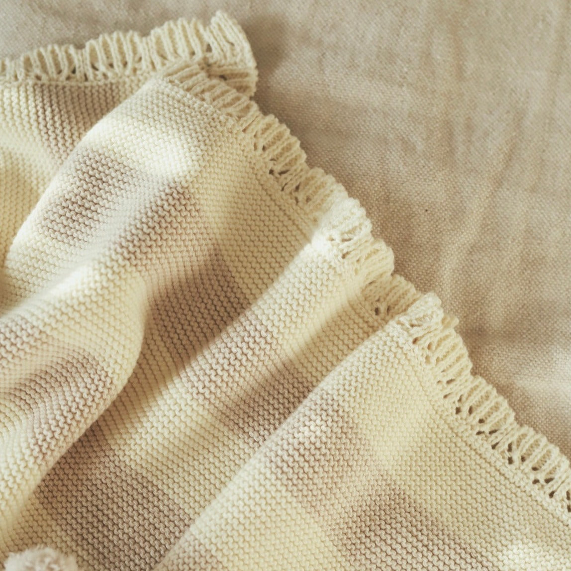 Close-up of a beige knitted fabric with a textured border.