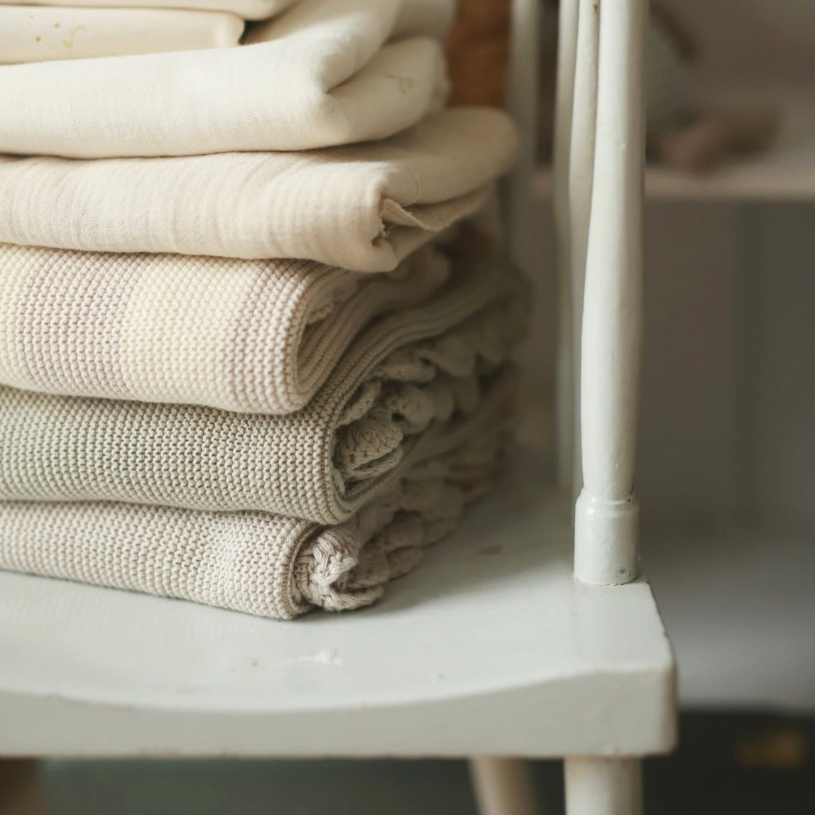 Stack of folded beige towels on a white shelf