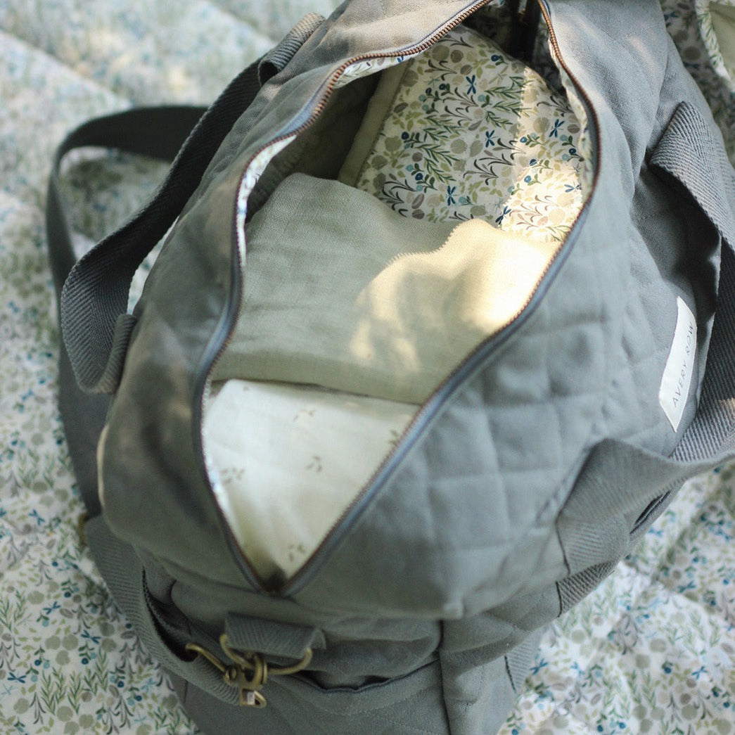 Gray duffel bag with floral lining on a textured surface