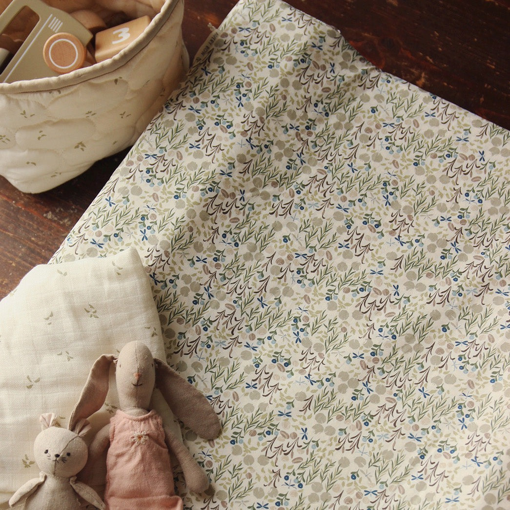 Floral-patterned fabric with soft toys on a wooden surface