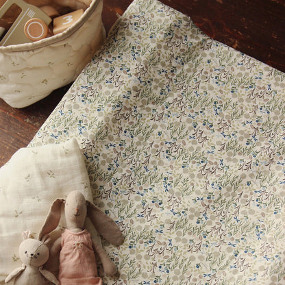 Floral-patterned fabric with soft toys on a wooden surface