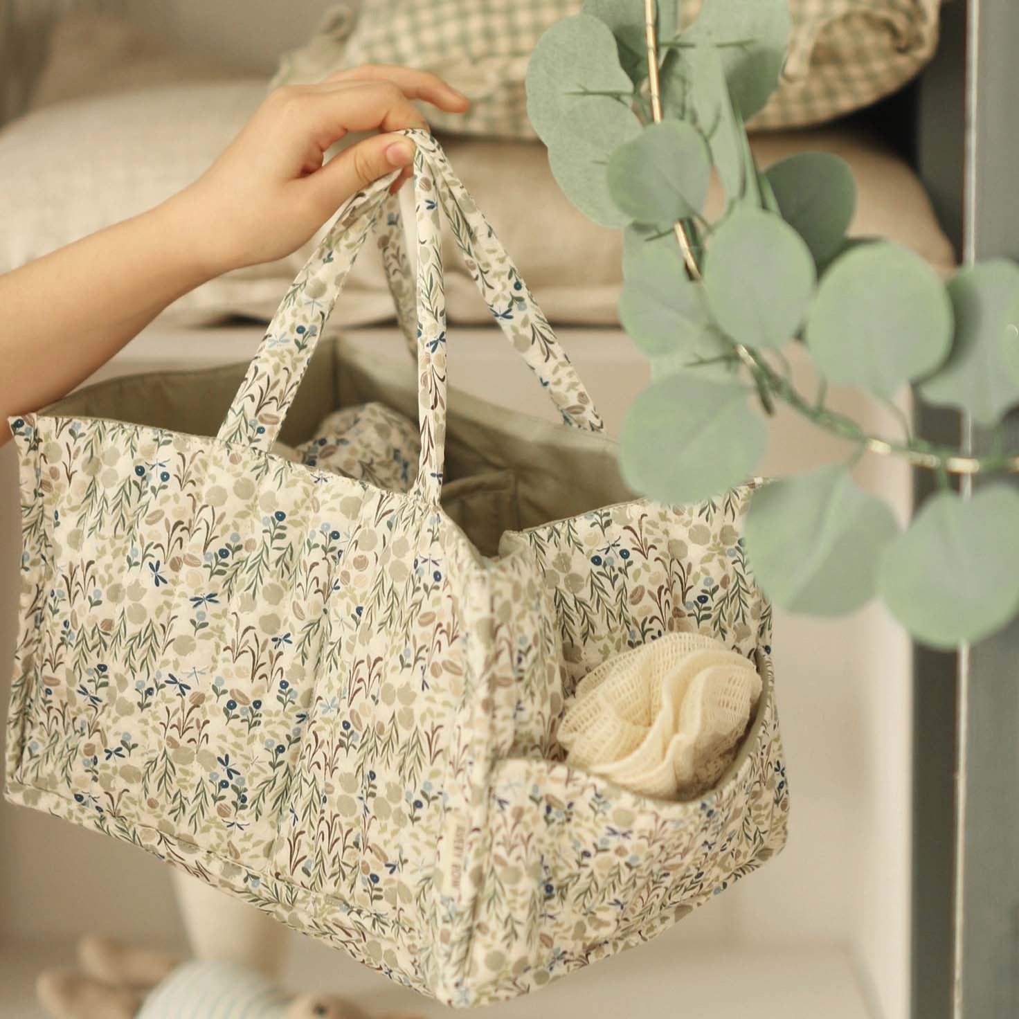 Floral-patterned bag held by a hand with a plant in the foreground