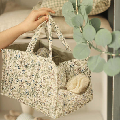 Floral-patterned bag held by a hand with a plant in the foreground
