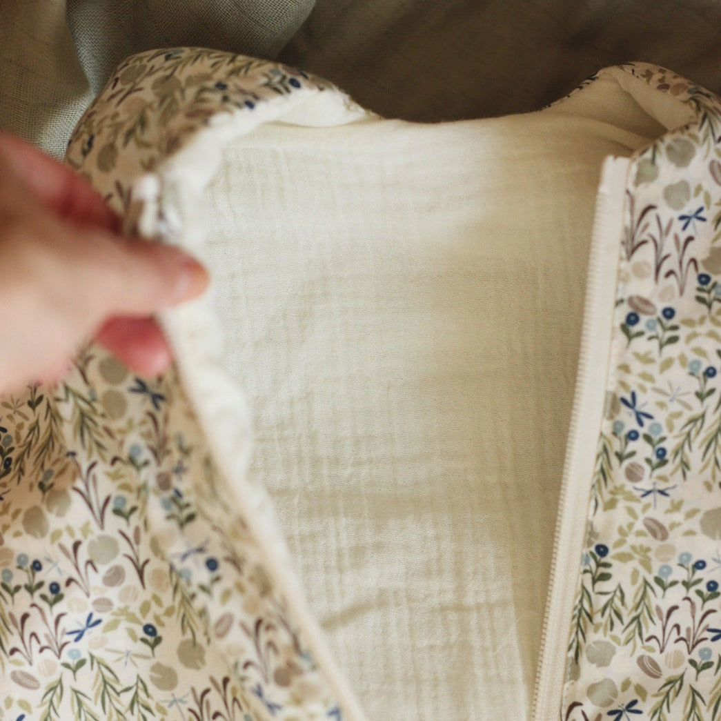 Close-up of a person holding a fabric item with floral patterns on a neutral background