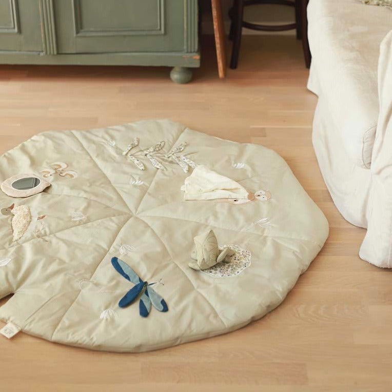 Decorative round mat with embroidered designs on a wooden floor.