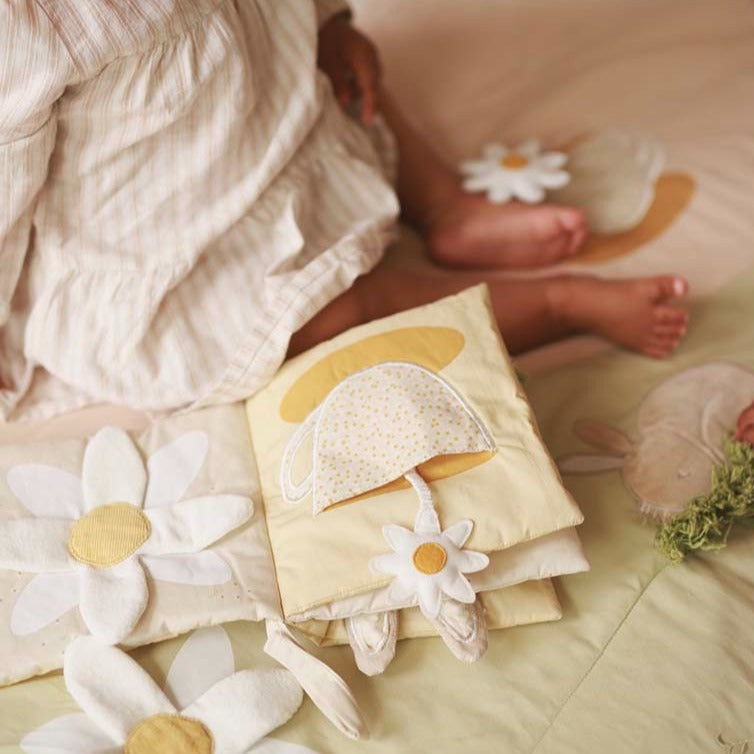 Baby in a white outfit with floral decorations on a soft surface