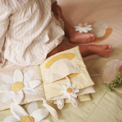 Baby in a white outfit with floral decorations on a soft surface